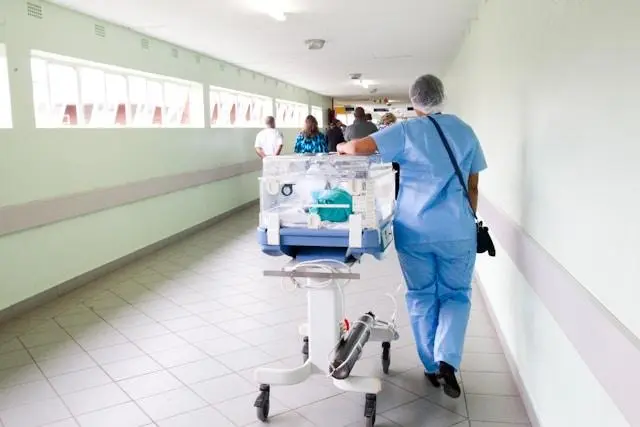 Advancements in technology improving chronic health care management, illustrated by a nurse transporting medical equipment in a hospital corridor.