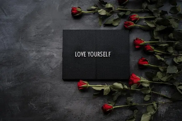 "Love Yourself message surrounded by red roses, symbolizing self-love and beauty in the context of plastic surgery."