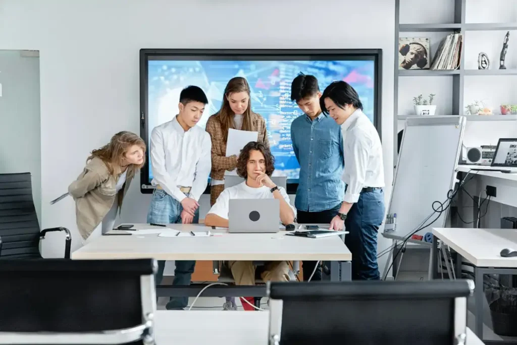 "IT support team discussing solutions in a modern office with a digital display"